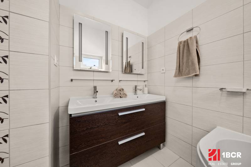 MODERNÝ 5-IZBOVÝ RODINNÝ DOM V ČUNOVE: 180m2 KOMFORTU A TICHA - Kúpeľňa v rodinnom dome s dvojitým umývadlom a tmavým kabinetom.