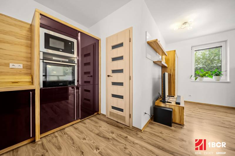 MODERNÝ 5-IZBOVÝ RODINNÝ DOM V ČUNOVE: 180m2 KOMFORTU A TICHA - Kuchyňa v rodinnom dome s podlahou s dreveným dekorom, modernými spotrebičmi a plávajúcimi policami.