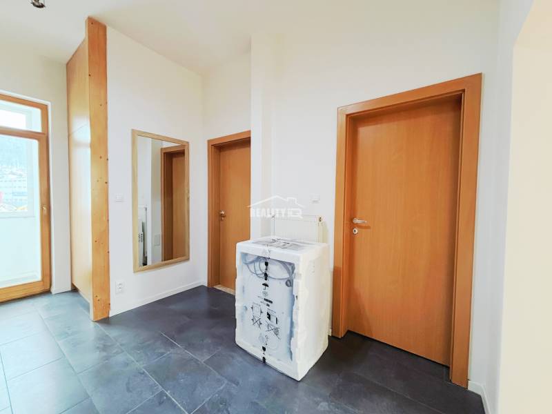 Prenájom, 2-izbový byt, M.R.Štefánika, Exkluzívne Reality IQ  - Chodba v 2-izbovom byte s tmavou podlahou a drevenými dverami.