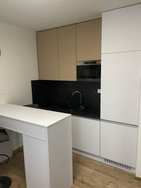 REZERVOVANÉ! Nadštandardný 1-izbový byt, ul. 1. mája, Vráble - Kuchynská linka v 1-izbovom byte s čiernym obkladom a podlahou s dreveným dekorom.