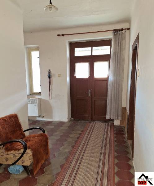 Všetko po čom túžite - dom, relax, kúpele, kúpalisko - Chodba rodinného domu s kachličkovou podlahou, kreslom a závesom.