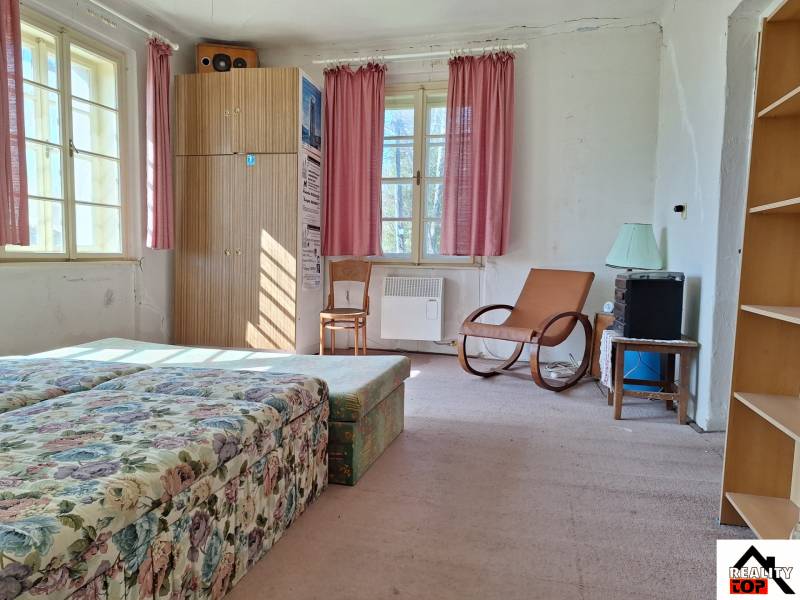 Všetko po čom túžite - dom, relax, kúpele, kúpalisko - Izba s kvetinovým gaučom, kreslom, skriňou a ružovými závesmi v rodinnom dome.