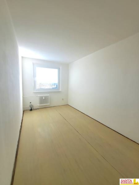 Na Predaj  4-izb. byt, Hornádska 28, Bratislava. - Izba v 4-izbovom byte s bielymi stenami a podlahou s dreveným dekorom.