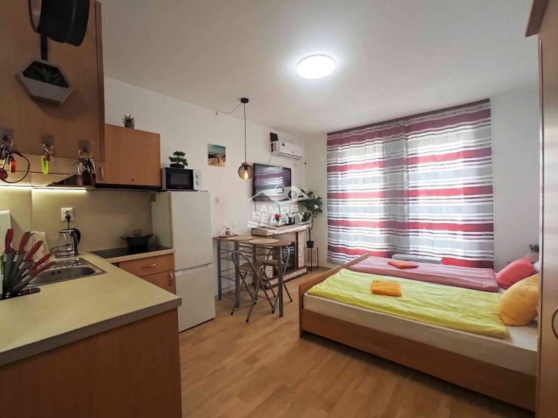 Predaj, štúdio 27 m2, rezort Sunny day, Slnečné pobrežie, Bulharsko - Rekreačný apartmán s útulnou kuchyňou, posteľou, televíziou a podlahou s dreveným dekorom.