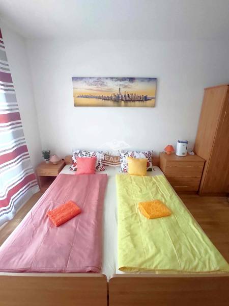 Predaj, štúdio 27 m2, rezort Sunny day, Slnečné pobrežie, Bulharsko - Spálňa v rekreačnom apartmáne s dvomi posteľami, obrazom a pestrofarebným povlečením.