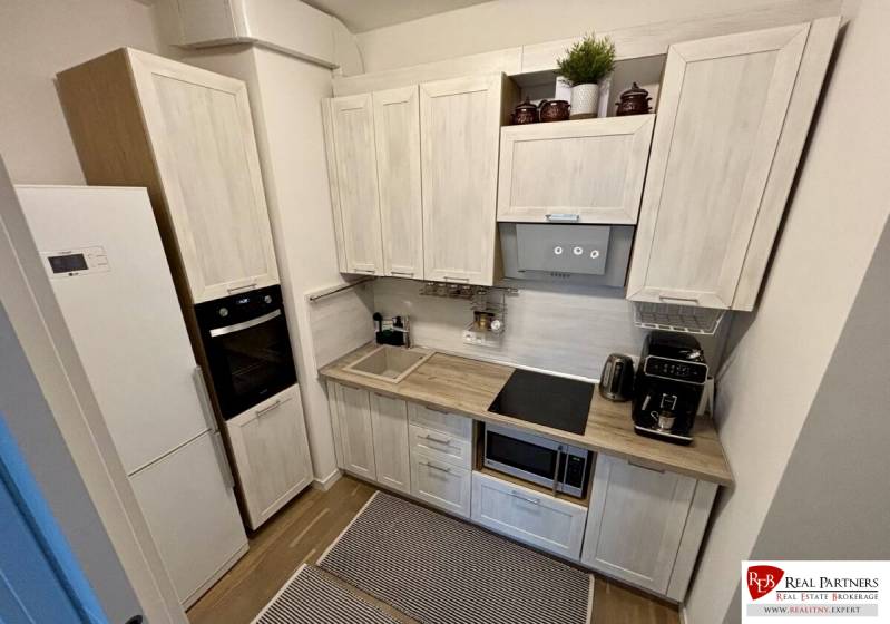 Prenájom 2-izbového bytu CUBICON  - Kuchyňa v 2-izbovom byte s podlahou s dreveným dekorom a modernými spotrebičmi.