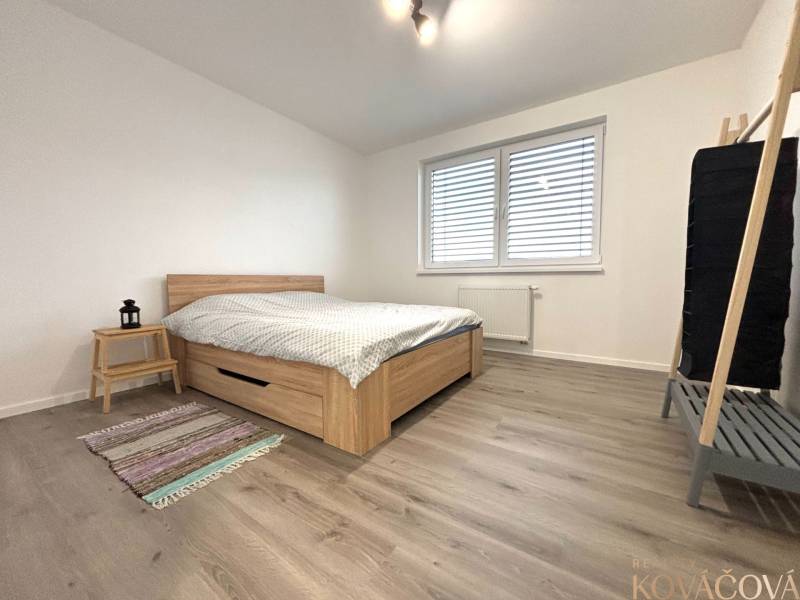 Na prenájom 3 izb. byt, Trenčín, ul.Vl.Predmerského, park.miesto,garáž - Spálňa v 3-izbovom byte s podlahou s dreveným dekorom a jednoduchým nábytkom.