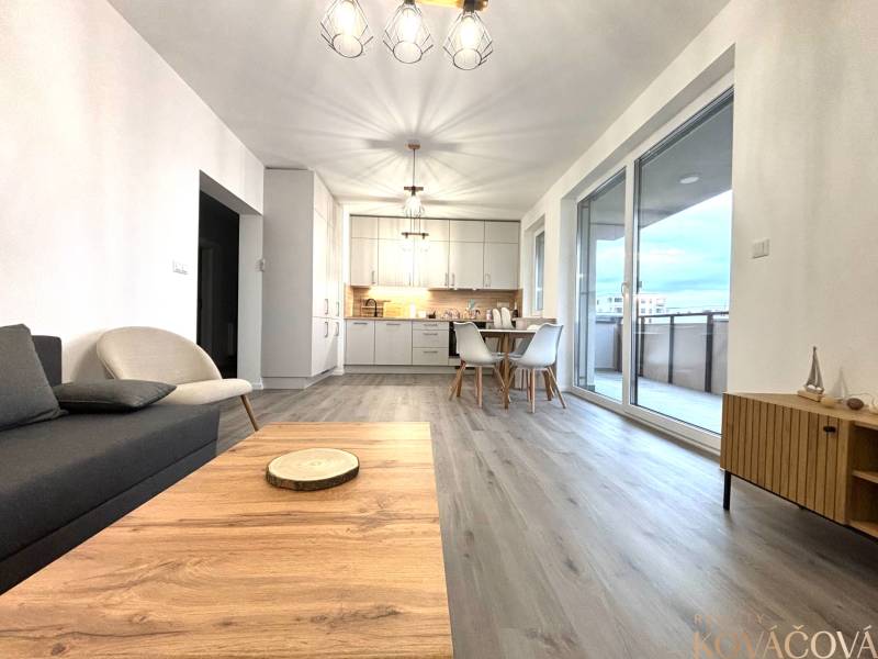 Na prenájom 3 izb. byt, Trenčín, ul.Vl.Predmerského, park.miesto,garáž - Obývacia izba s podlahou s dreveným dekorom a jedálenským stolom v 3-izbovom byte.