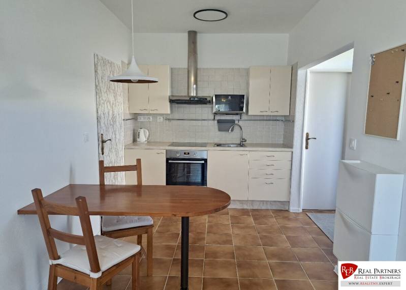 Prenájom útulný 2,5-izbový byt so záhradkou Vajnory - Kuchyňa v 3-izbovom byte s keramickou podlahou, stolom a stoličkami.