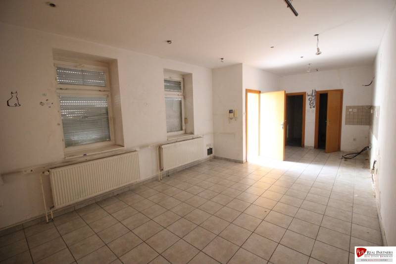 Ponúka na predaj budovu - centrum Senca - NOVÁ SUPER CENA  - Prázdna miestnosť s radiátormi, oknami, dlažbou; priestor na ulici Mierové nám. a budova.