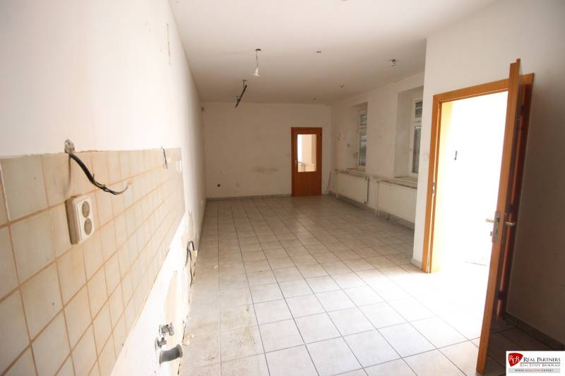 Ponúka na predaj budovu - centrum Senca - NOVÁ SUPER CENA  - Prázdna miestnosť na Mierové nám., s obkladačkami, radiátormi a dverami, čakajúca na renováciu.