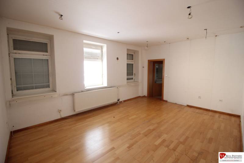 Ponúka na predaj budovu - centrum Senca - NOVÁ SUPER CENA  - Prázdna izba s drevenou podlahou, oknami a radiátorom. Na ulici Mierové nám. budova.