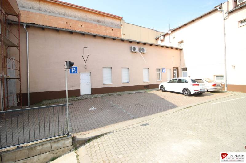 Ponúka na predaj budovu - centrum Senca - NOVÁ SUPER CENA  - Parkovisko na ulici Mierové nám., budova, dve autá, parkovacie značenie.