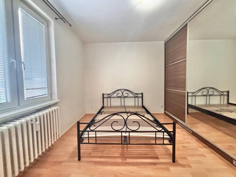 Predaj: Veľkometrážny 3+1 byt v Turzovke - Spálňa s kovovou posteľou, vstavanou skriňou a podlahou s dreveným dekorom v 3-izbovom byte.