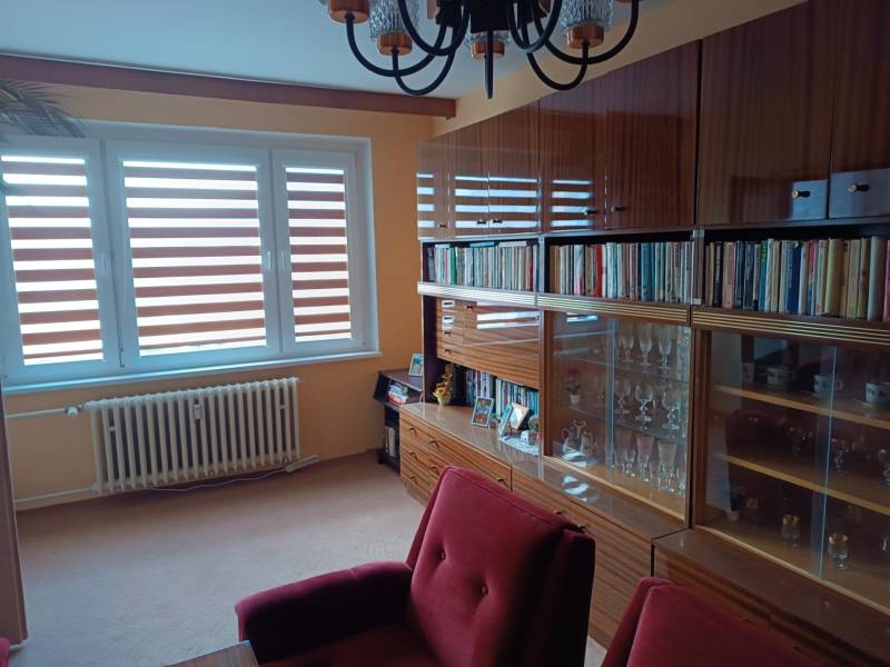 Na predaj veľkometrážny 3 izbový byt Žarnovica - Obývacia izba v 3-izbovom byte so skriňou a čítacím kútikom, podlaha s dreveným dekorom.