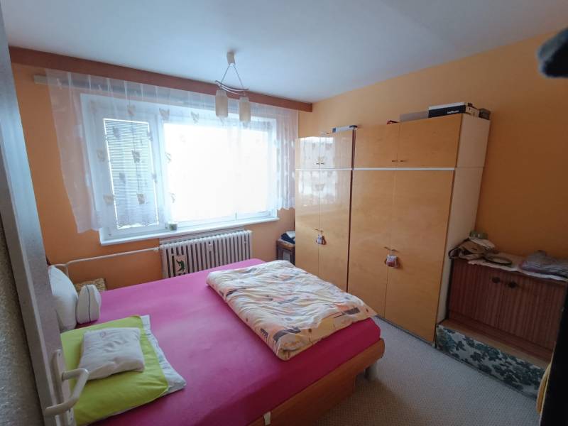 Na predaj veľkometrážny 3 izbový byt Žarnovica - Spálňa v 3-izbovom byte s posteľou a skriňou, okno s oblúkovou záclonou.