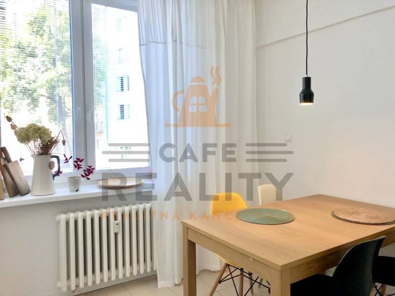 Na prenájom 2 izbový byt, 56 m2, Bratislava, Staré Mesto, Björnsonova - Svietidlo nad dreveným stolom, biele záclony a dekór kvetov na parapete v 2-izbovom byte.