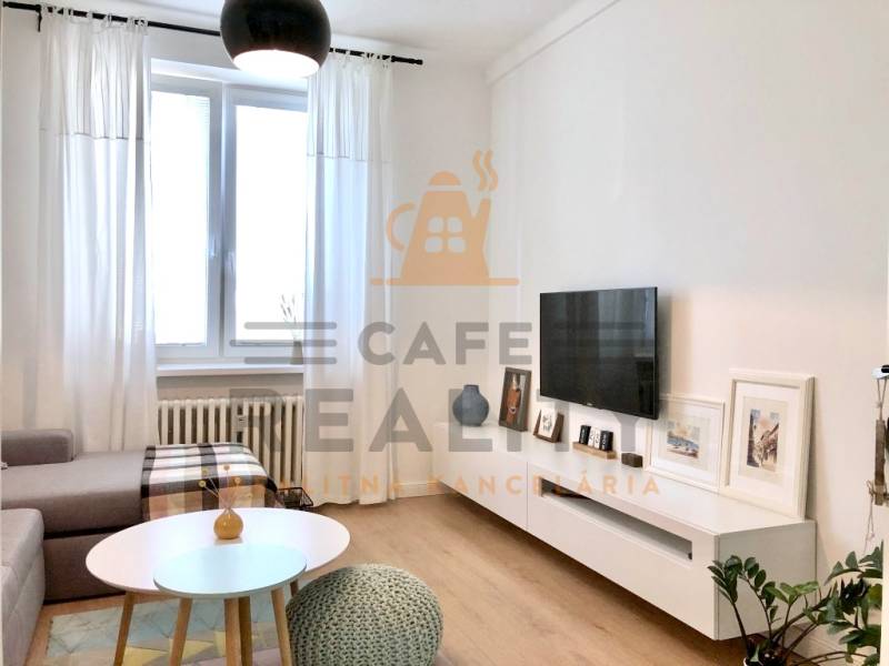 Na prenájom 2 izbový byt, 56 m2, Bratislava, Staré Mesto, Björnsonova - Obývacia izba v 2-izbovom byte s televízorom, pohovkou a podlahou s dreveným dekorom.