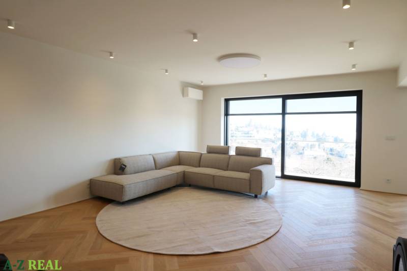 Prenájom 4 izbového bytu s krásnym výhľadom na mesto - Obývačka v 4-izbovom byte s pohovkou, oknom a podlahou s dreveným dekorom.