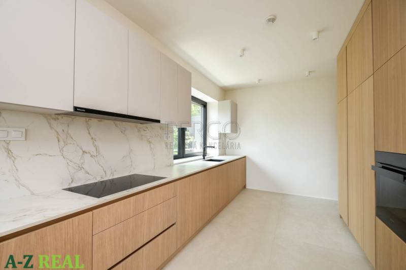 Prenájom 4 izbového bytu s krásnym výhľadom na mesto - Kuchyňa v 4-izbovom byte s bielymi skrinkami, mramorovým povrchom a dreveným dekorom.