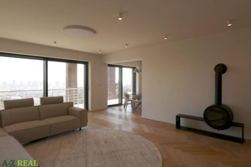 Prenájom 4 izbového bytu s krásnym výhľadom na mesto - Obývacia izba so sedačkou, krbom a podlahou s dreveným dekorom v 4-izbovom byte.