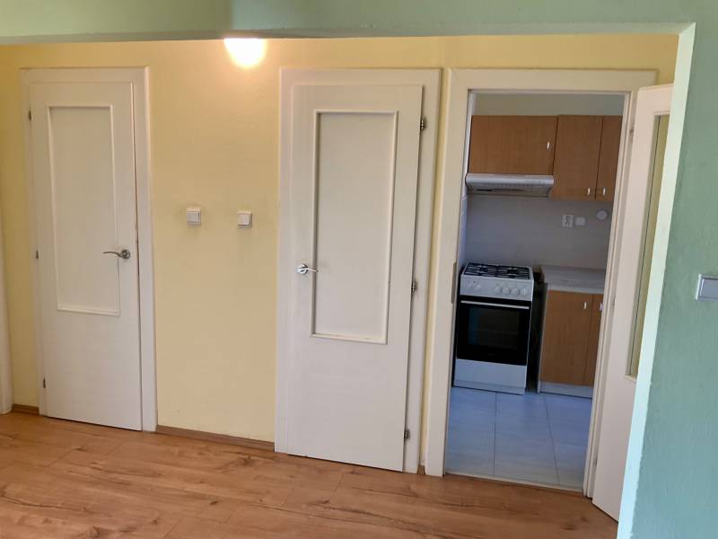 I prenájom štýlových izieb v 3-izbovom byte – Karlova Ves - Interiér 3-izbového bytu s podlahou s dreveným dekorom a kuchynskou linkou.