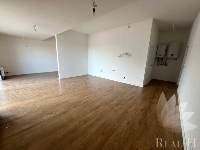 PREDAJ VEĽKORYSÝ 2 IZBOVÝ BYT NOVOSTAVBA DESINGN CENTER - Interiér 2-izbového bytu s podlahou s dreveným dekorom, biele steny, otvorený priestor.