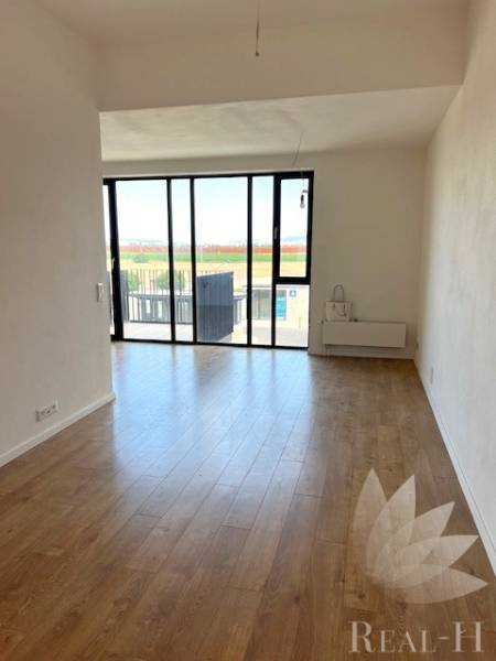 PREDAJ VEĽKORYSÝ 2 IZBOVÝ BYT NOVOSTAVBA DESINGN CENTER - Svetlá obývacia izba s veľkými oknami a podlahou s dreveným dekorom v 2-izbovom byte.