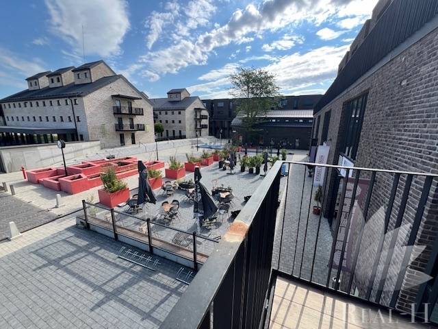 PREDAJ VEĽKORYSÝ 2 IZBOVÝ BYT NOVOSTAVBA DESINGN CENTER - Exteriér Námestia pri Sýpke v Bratislava - Jarovce s terasou a tehlovými budovami.