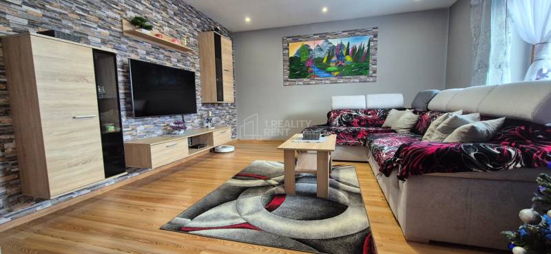 Predaj: Rodinný dom po rekonštrukcii s nadstavbou v Ochodnici (RCZ) - Obývačka v rodinnom dome s podlahou s dreveným dekorom, kameňom na stene a pohodlnou sedačkou.