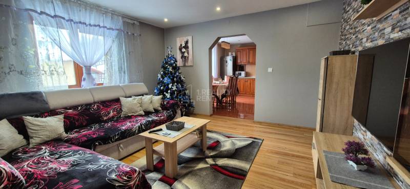 Predaj: Rodinný dom po rekonštrukcii s nadstavbou v Ochodnici (RCZ) - V obývačke rodinného domu je sedačka, vianočný stromček a podlaha s dreveným dekorom.