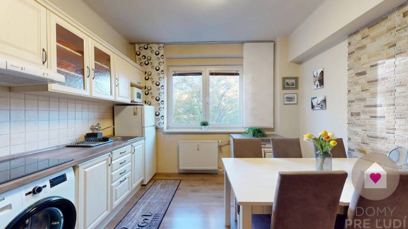 BA/STARÉ MESTO - Prenájom kompletne zariadeného 2i bytu s 2 balkónmi - Kuchyňa v 2-izbovom byte s podlahou s dreveným dekorom, jedálenským stolom a kvetmi.