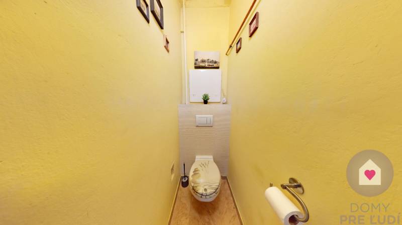 BA/STARÉ MESTO - Prenájom kompletne zariadeného 2i bytu s 2 balkónmi - Toaleta s podlahou s dreveným dekorom v 2-izbovom byte, žlté steny, dekorácie na stenách.