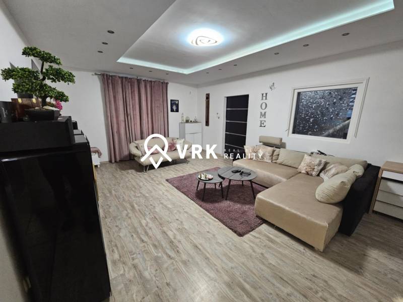 RODINNÝ DOM, HERNÁDKAK, MAĎARSKO - Obývačka v rodinnom dome s podlahou s dreveným dekorom a veľkou sedačkou.