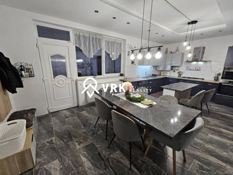 RODINNÝ DOM, HERNÁDKAK, MAĎARSKO - Jedálenský priestor s kamenným stolom, sivými stoličkami a závesnými svetlami v rodinnom dome.