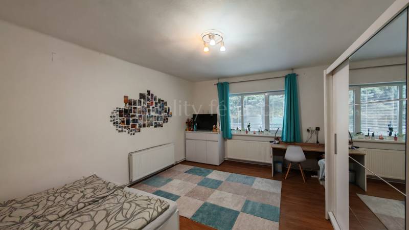 Na predaj rodinný dom v Trnovci nad Váhom - Izba v rodinnom dome s písacím stolom, posteľou, fotkami na stene a podlahou s dreveným dekorom.