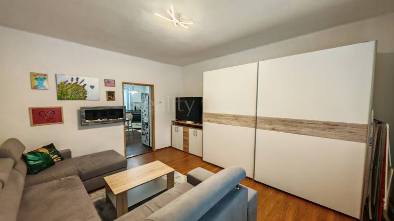 Na predaj rodinný dom v Trnovci nad Váhom - Obývačka v rodinnom dome s podlahou s dreveným dekorom, sedačkou a obrazmi na stene.