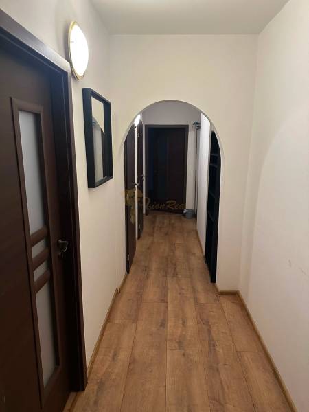 2-izb. byt, Nejedlého, Dúbravka, izby samostatné - Úzky chodba v 2-izbovom byte s podlahou s dreveným dekorom a tmavými dverami.