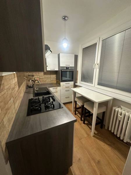 2-izb. byt, Nejedlého, Dúbravka, izby samostatné - Kuchyňa v 2-izbovom byte s podlahou s dreveným dekorom a plynovým sporákom.