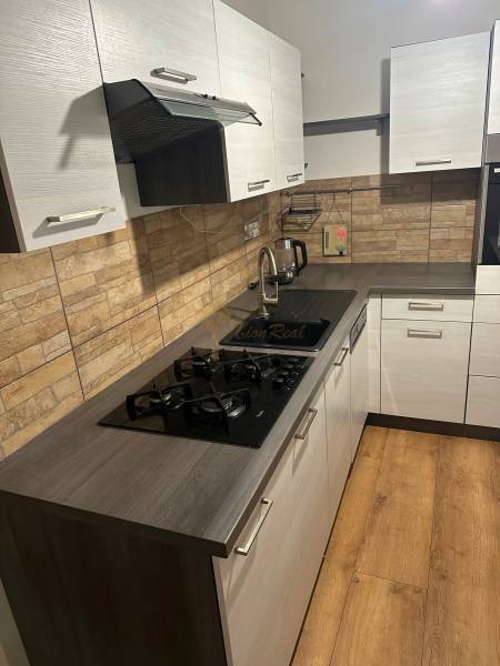 2-izb. byt, Nejedlého, Dúbravka, izby samostatné - Kuchyňa v 2-izbovom byte s plynovým sporákom, moderným obkladom a podlahou s dreveným dekorom.