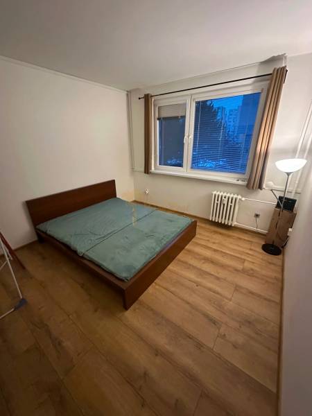 2-izb. byt, Nejedlého, Dúbravka, izby samostatné - Spálňa v 2-izbovom byte s posteľou a podlahou s dreveným dekorom.