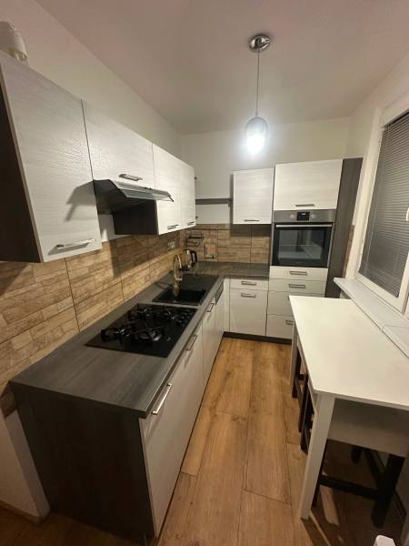 2-izb. byt, Nejedlého, Dúbravka, izby samostatné - Kuchyňa v 2-izbovom byte s podlahou s dreveným dekorom a stenami z tehál.