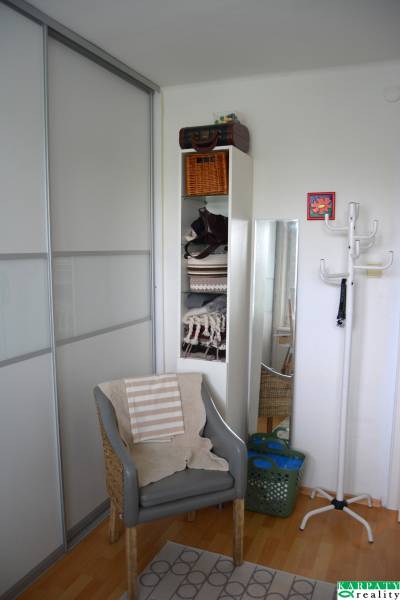 Útulný 3-izbový byt v Trnave na skok do Kamenáča! - Pohodlné kreslo s podlahou s dreveným dekorom v 3-izbovom byte.