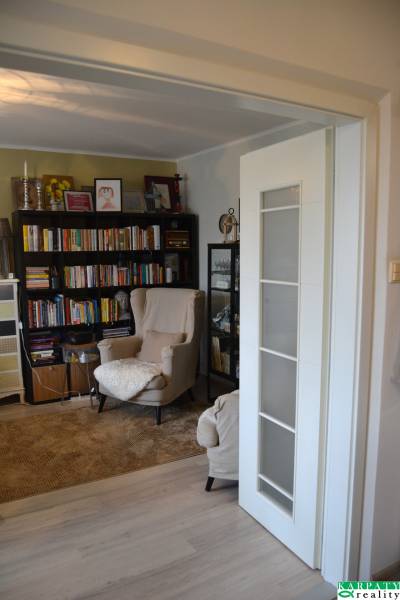 Útulný 3-izbový byt v Trnave na skok do Kamenáča! - Čitateľský kútik s pohodlným kreslom a knihami v 3-izbovom byte s podlahou s dreveným dekorom.