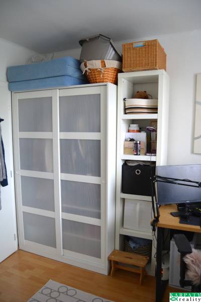 Útulný 3-izbový byt v Trnave na skok do Kamenáča! - Interiér 3-izbového bytu s bielou skriňou a poličkami, podlaha s dreveným dekorom.