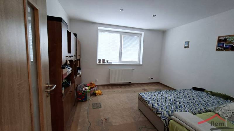 Dom na predaj Nová Ves nad Žitavou, pozemok 732 m2 - Izba v rodinnom dome s posteľou, nábytkom a podlahou s dreveným dekorom.