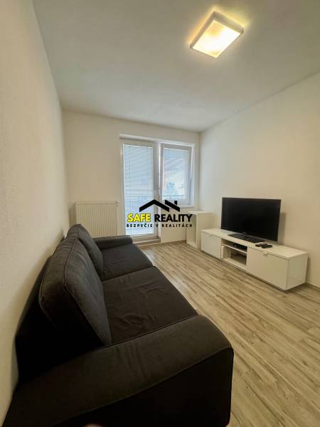 PRENÁJOM 2-izbový byt, Žilina - Slnečné terasy - Obývacia izba v 2-izbovom byte s pohovkou, televízorom a podlahou s dreveným dekorom.