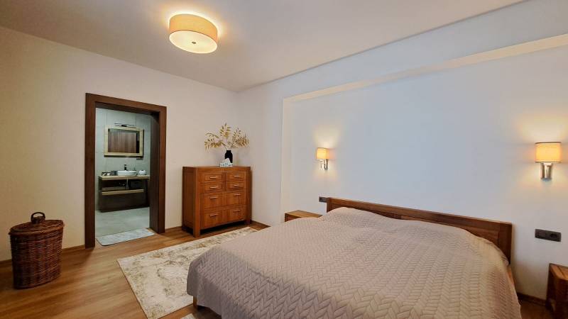 Lukratívny a priestranný 2-izbový apartmán v Mlynici na prenájom - Spálňa v 2-izbovom byte s posteľou, dreveným nábytkom a podlahou s dreveným dekorom.