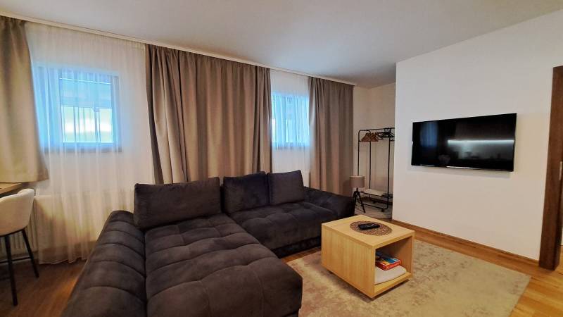 Lukratívny a priestranný 2-izbový apartmán v Mlynici na prenájom - Obývacia izba v 2-izbovom byte s pohodlnou sedacou súpravou a podlahou s dreveným dekorom.