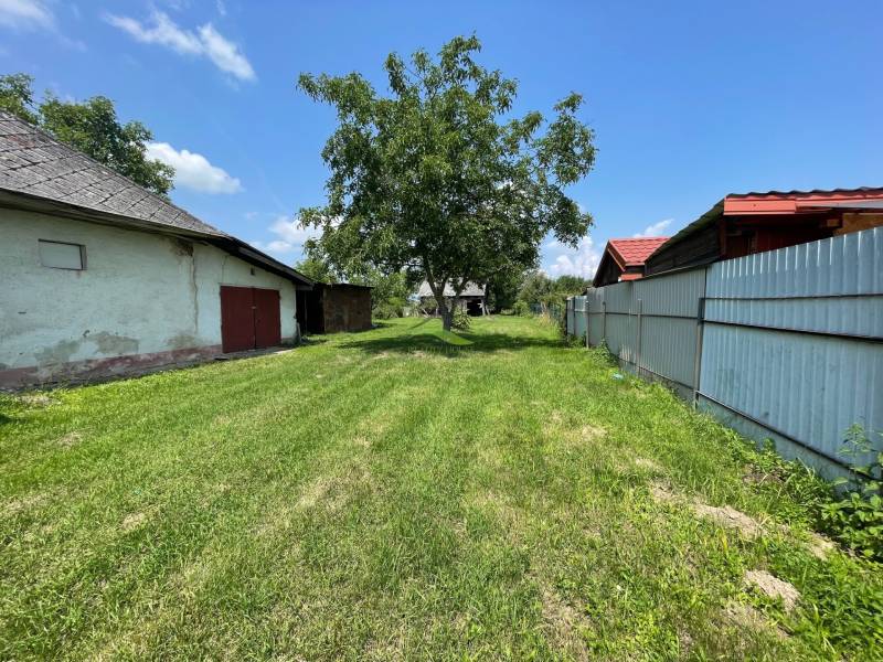 Super pozemok pre rodinný dom blízko mesta - Výhľad na zelený pozemok v Zemplínskej Širokej, ideálny na bývanie, s viditeľnými budovami.